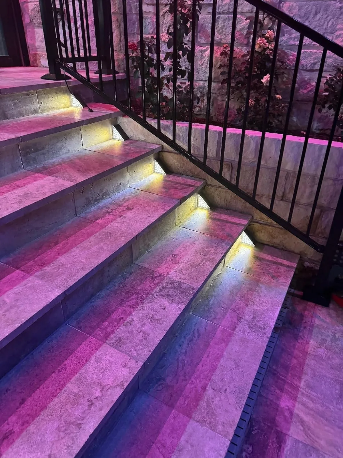 Solar step lights glowing on outdoor stairs beside a railing