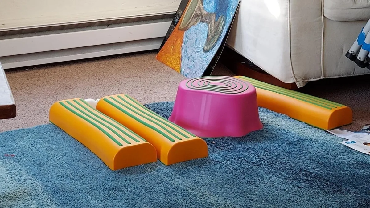 Plastic balance logs and a stepping stump arranged on a carpet near a couch