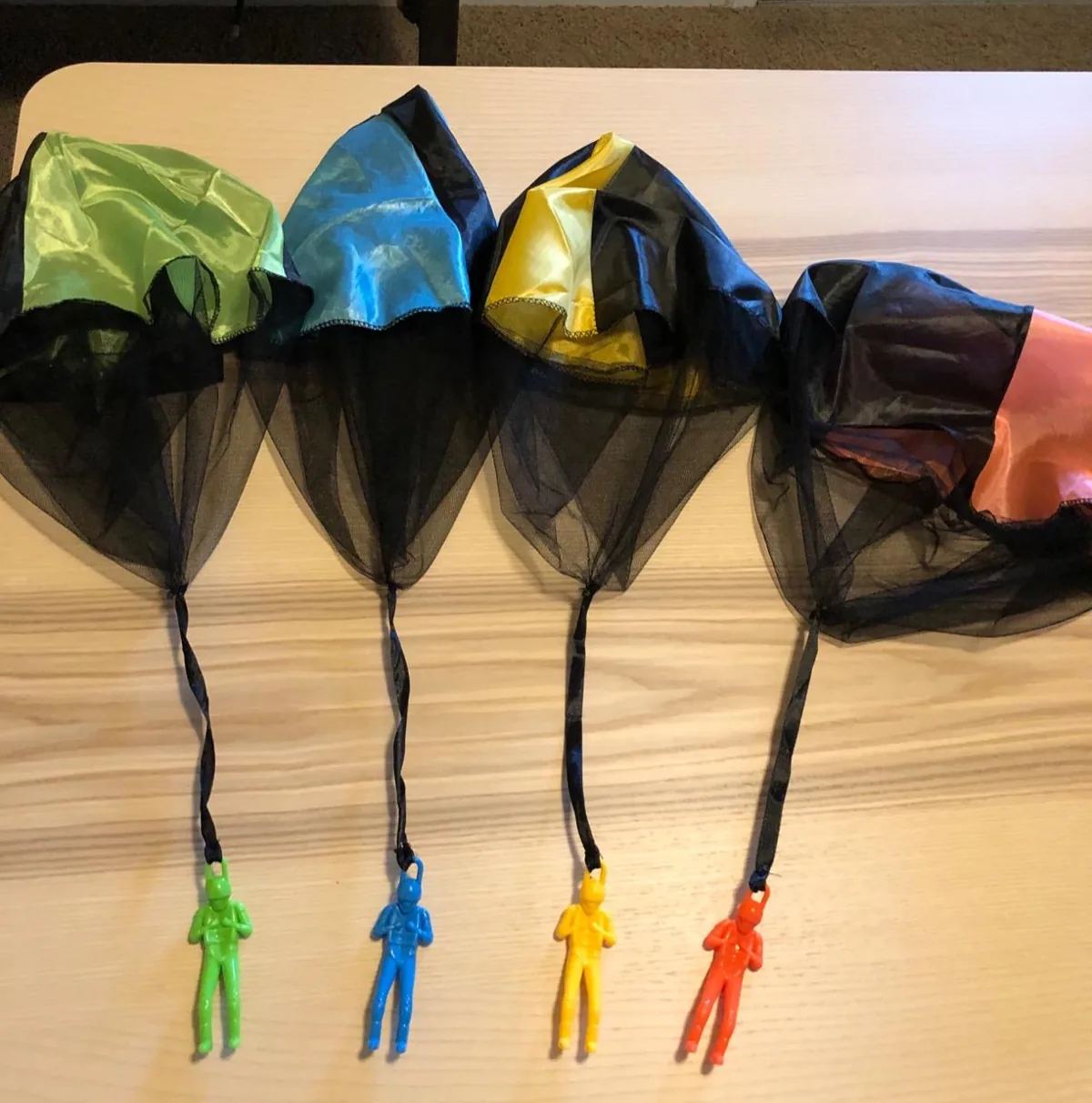 Four toy parachutes with little figures in different colors