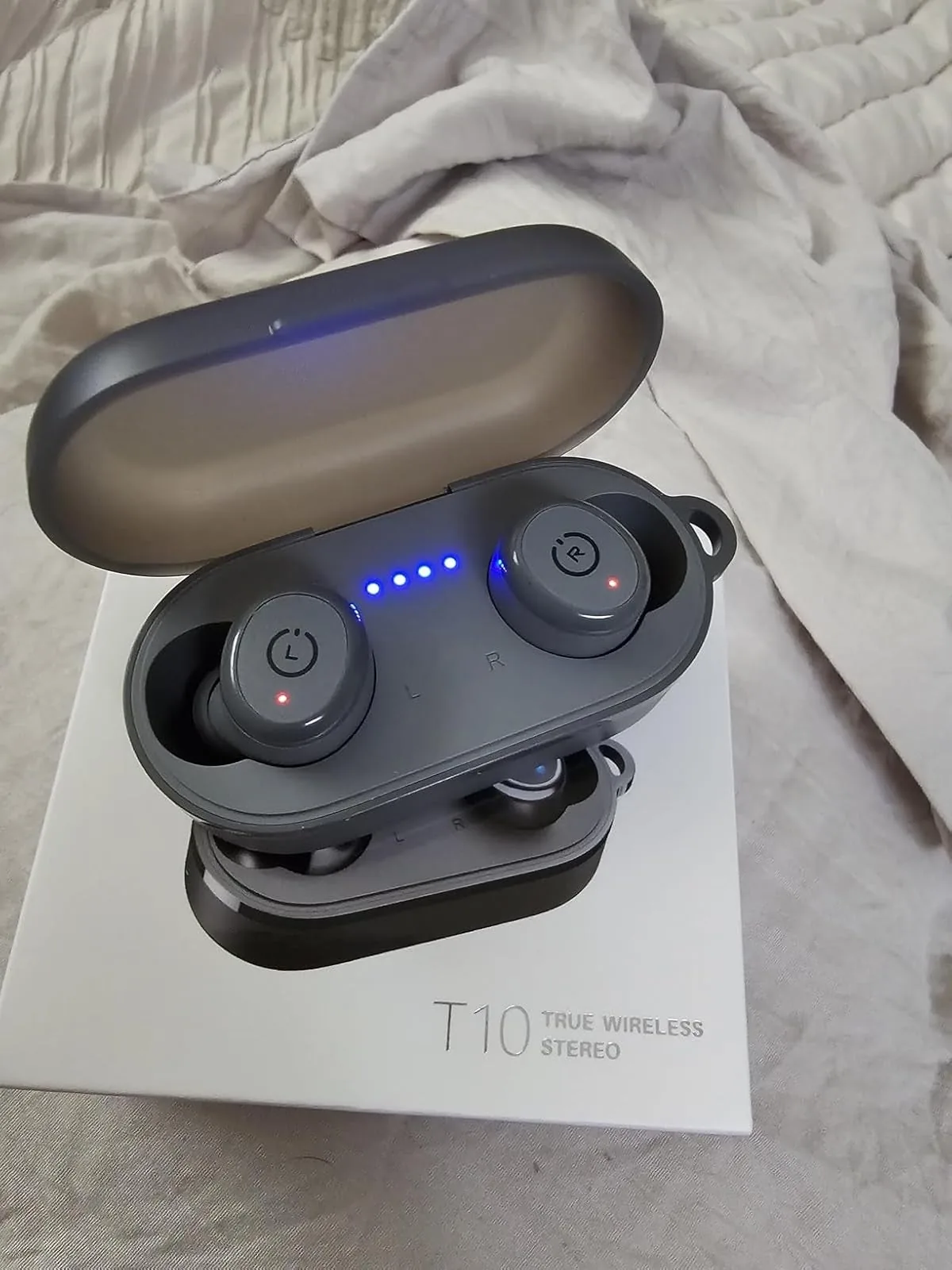 Tozo wireless earbuds in their open charging case resting on the box