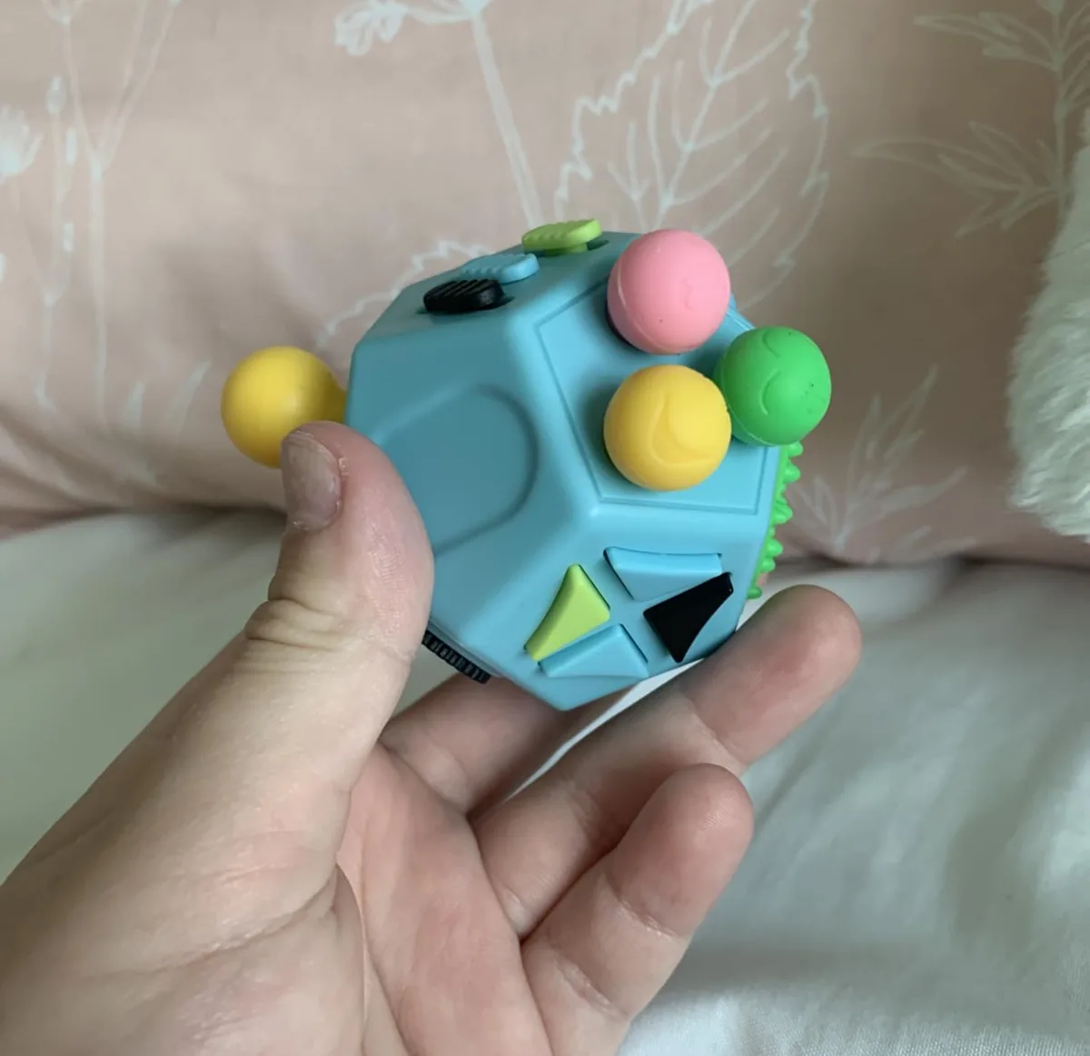 Blue twelve-sided fidget toy with buttons and balls held in a hand