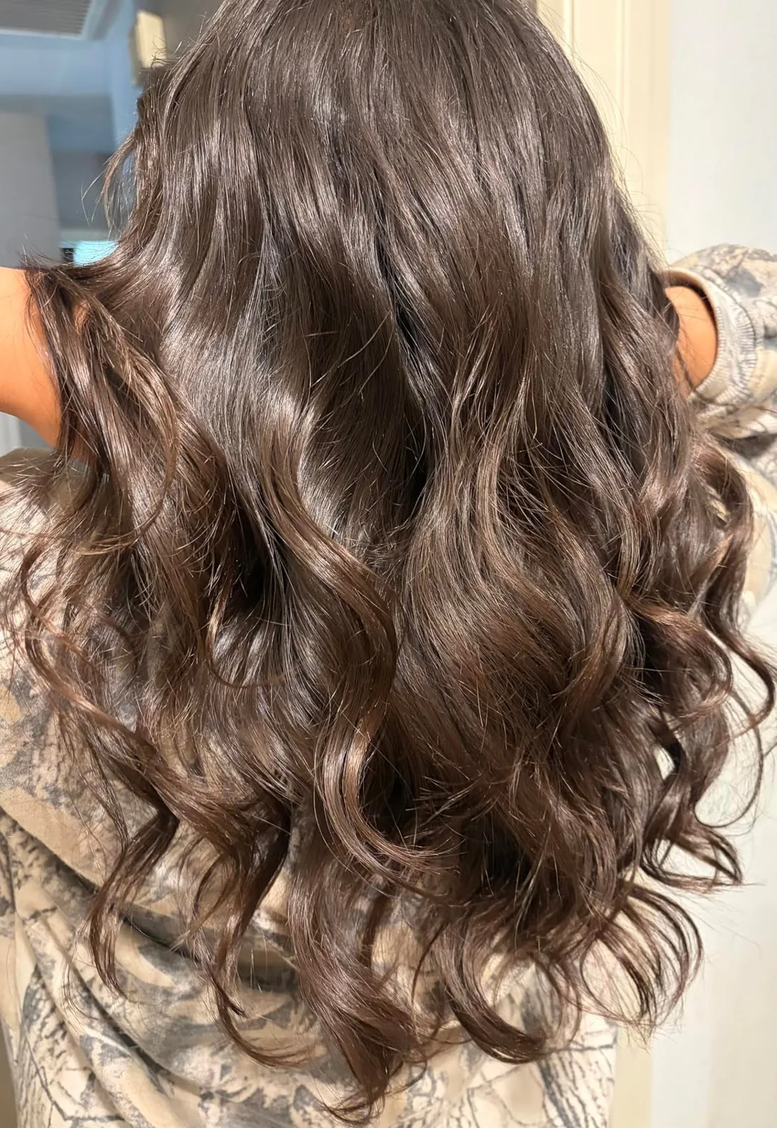 Long brown hair in loose waves styled with an automatic rotating curler