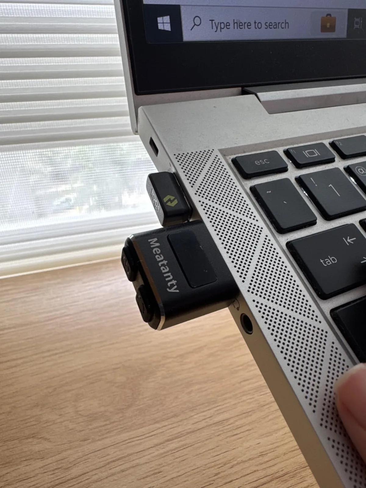 Small USB mouse jiggler plugged into the side of a laptop