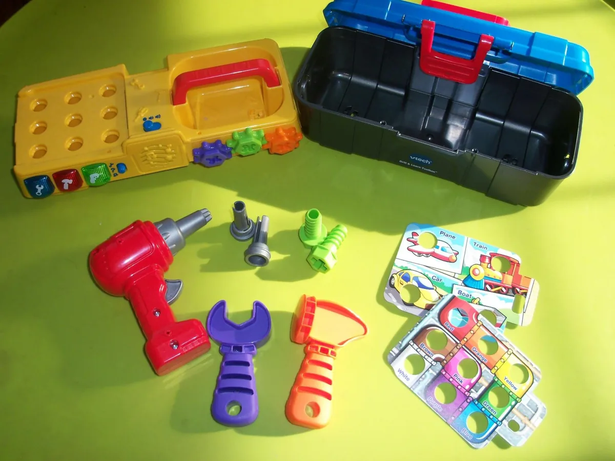Toy toolbox with a red drill, wrench, hammer, bolts and colorful pattern cards on a table