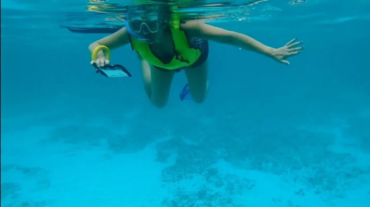 Swimmer holding a phone in a waterproof case underwater