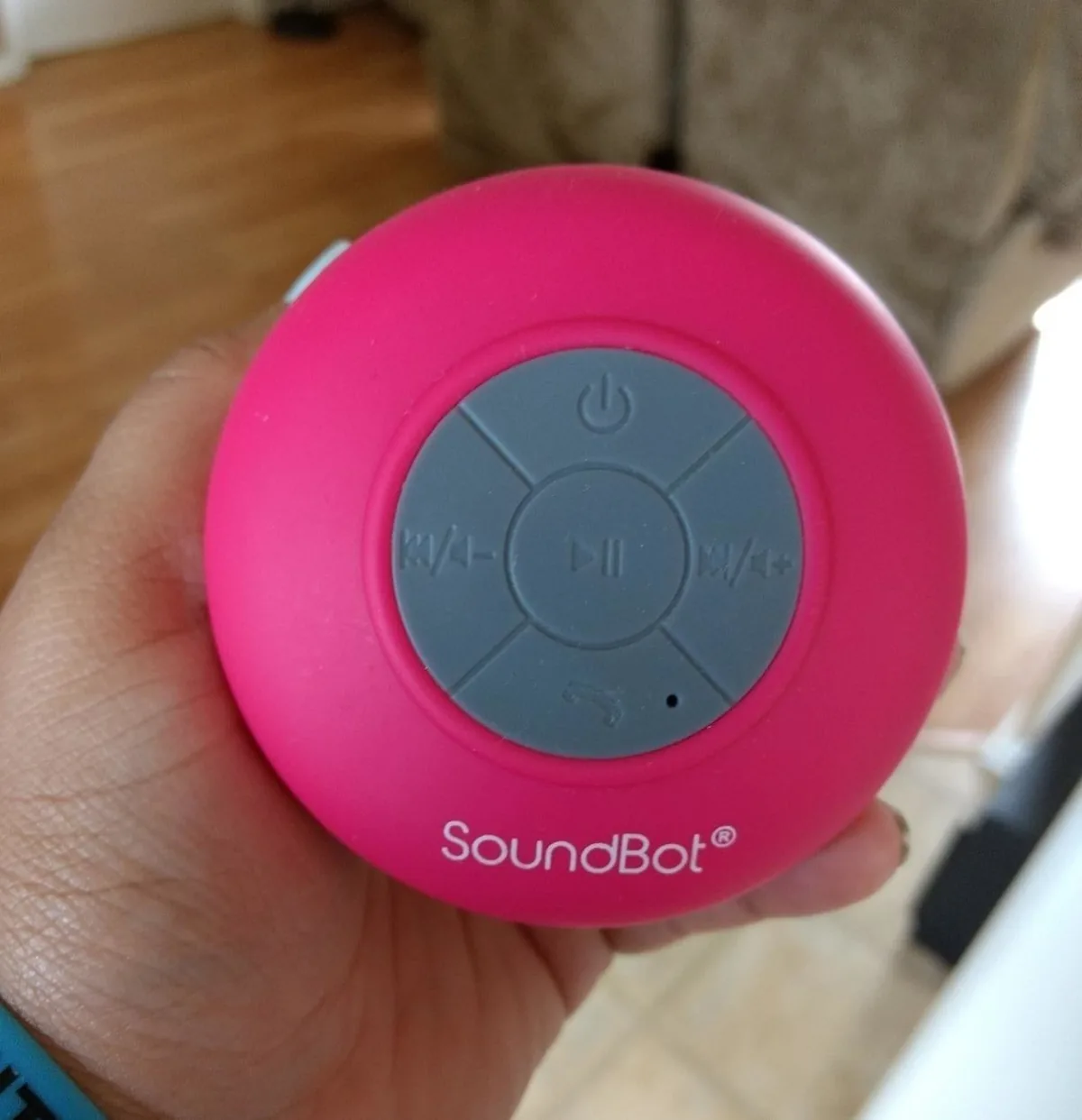 Hand holding a pink waterproof Bluetooth shower speaker