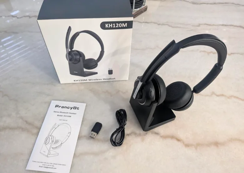 Wireless call center headset on its charging stand next to the box, USB dongle and cable